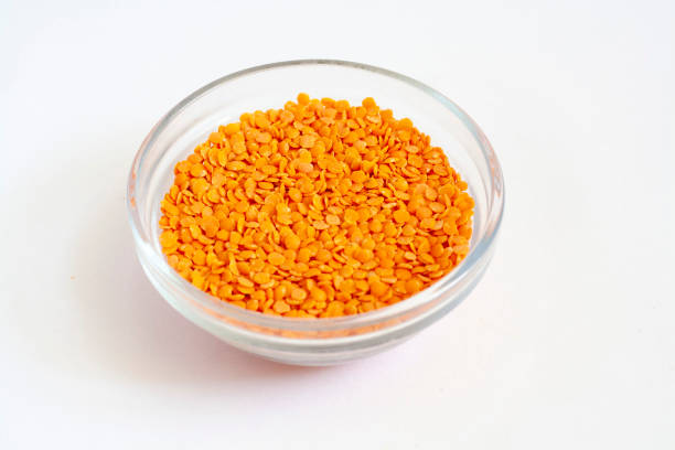 Red lentils in a glass bowl isolated on a white background